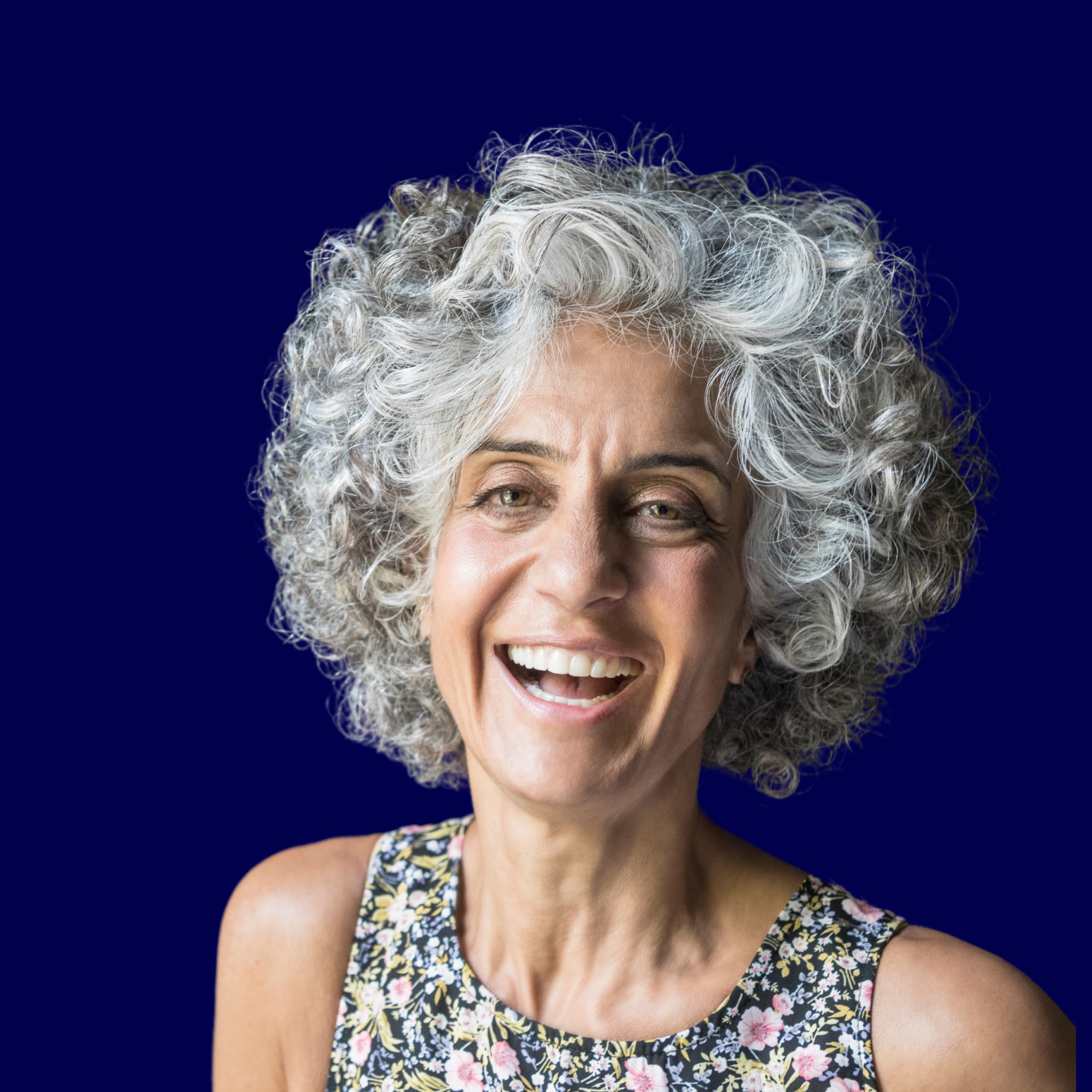An older woman laughing warmly against a deep navy background