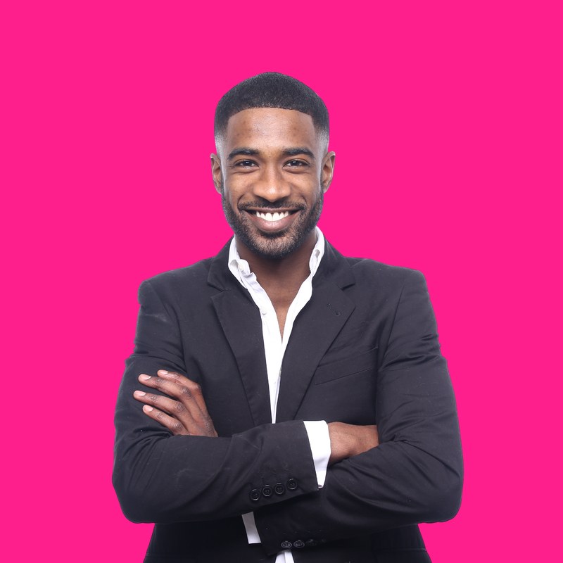 A polished, warm professional in a dark suit against a hot pink background