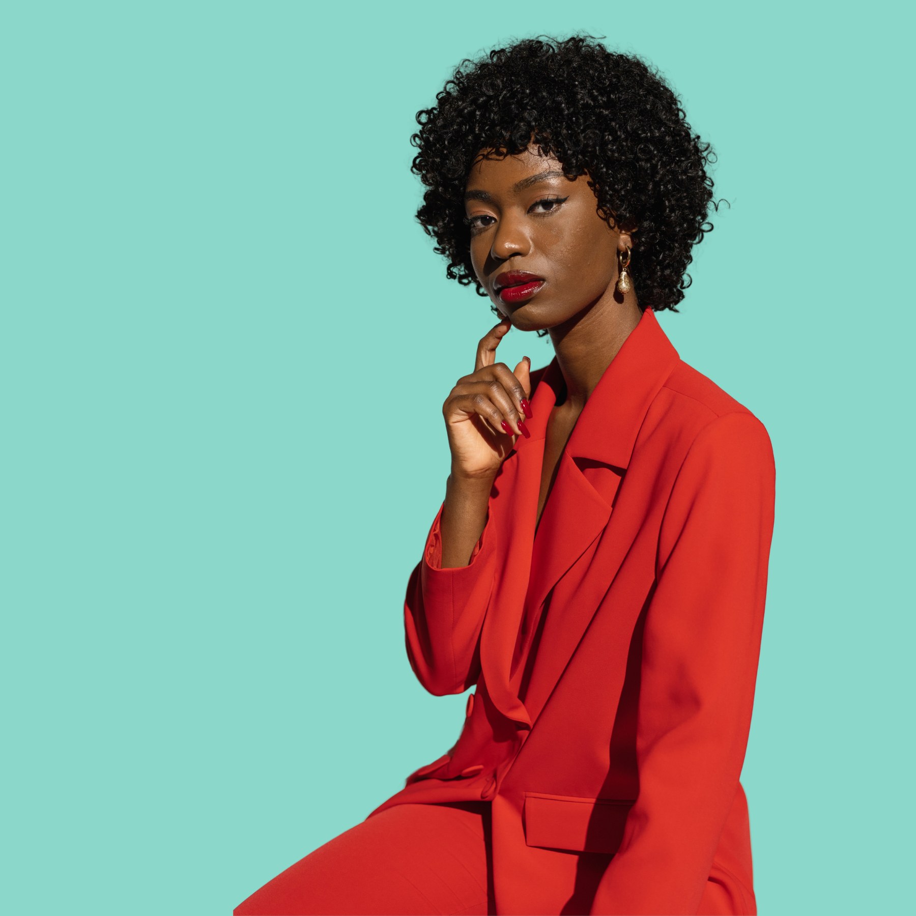 A practitioner in a red blazer with a phone, conveying ready communication energy against a marine background