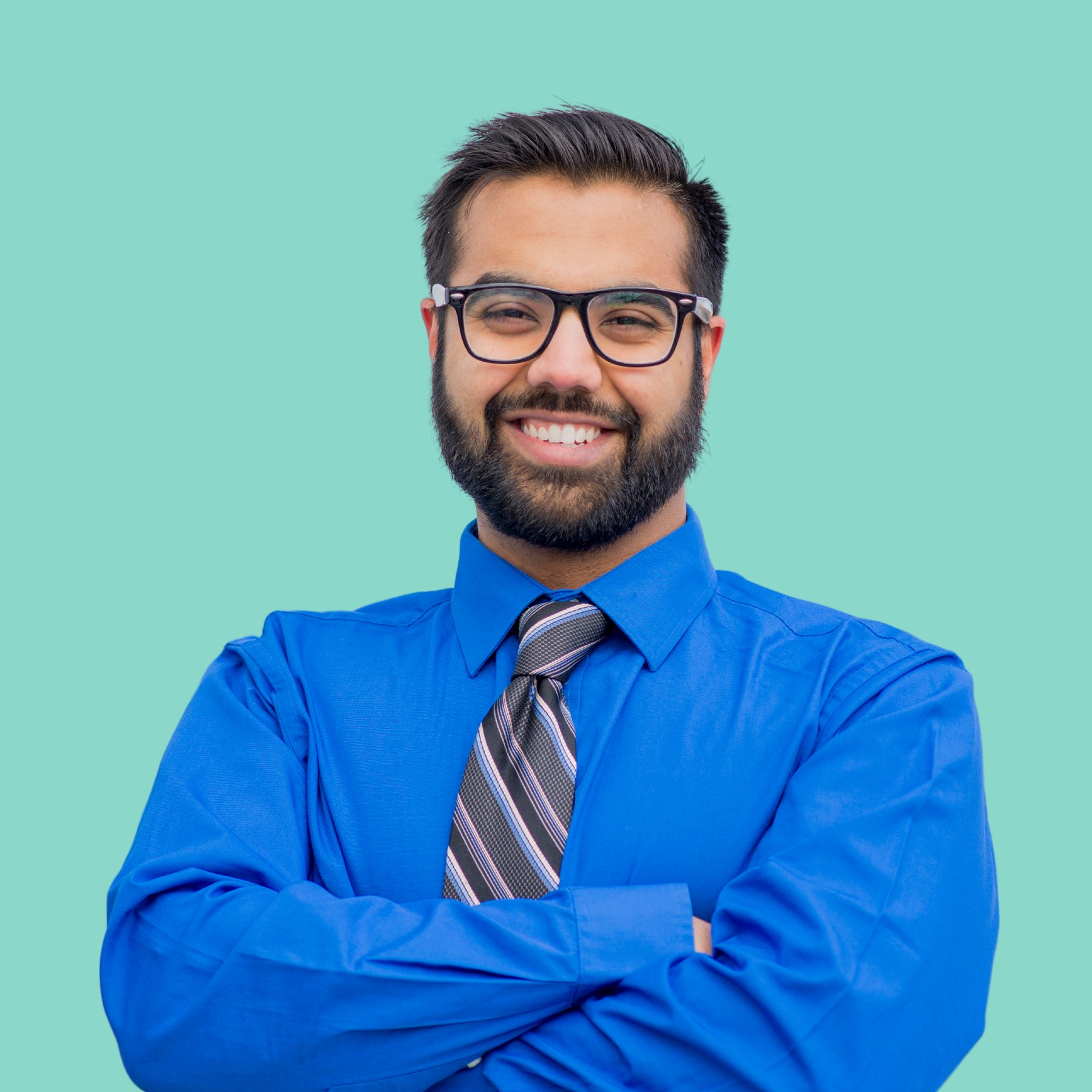 A professional in a blue shirt and tie with a composed, policy-minded presence against a marine background
