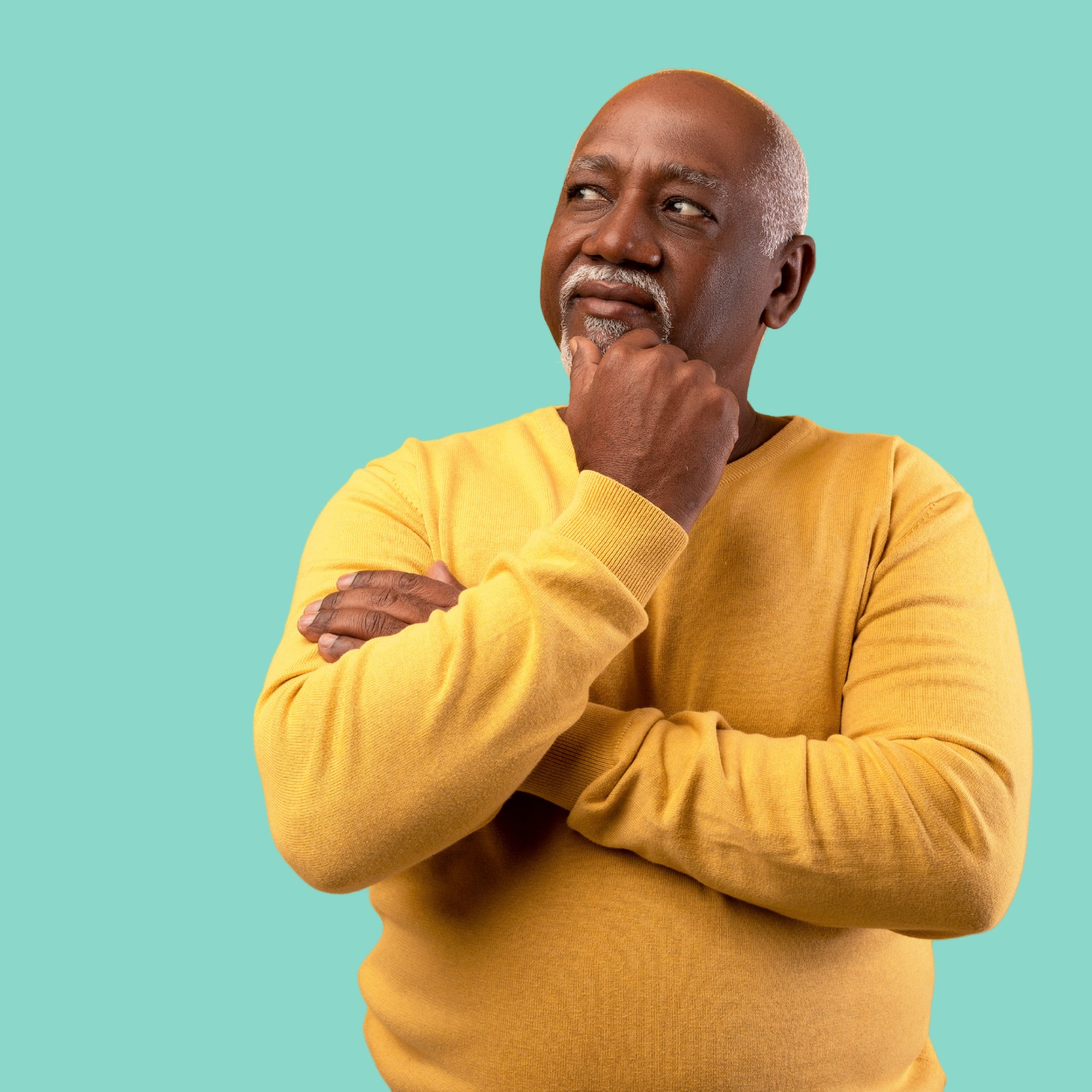 A practitioner in a yellow long-sleeve top in a thoughtful study pose against a marine background