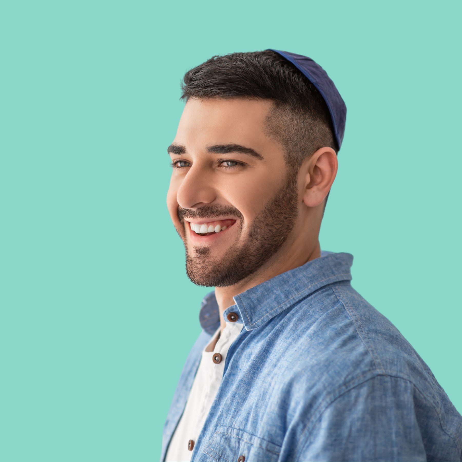 A practitioner in a flat cap mid-laugh, with engaged and enthusiastic presence against a marine background