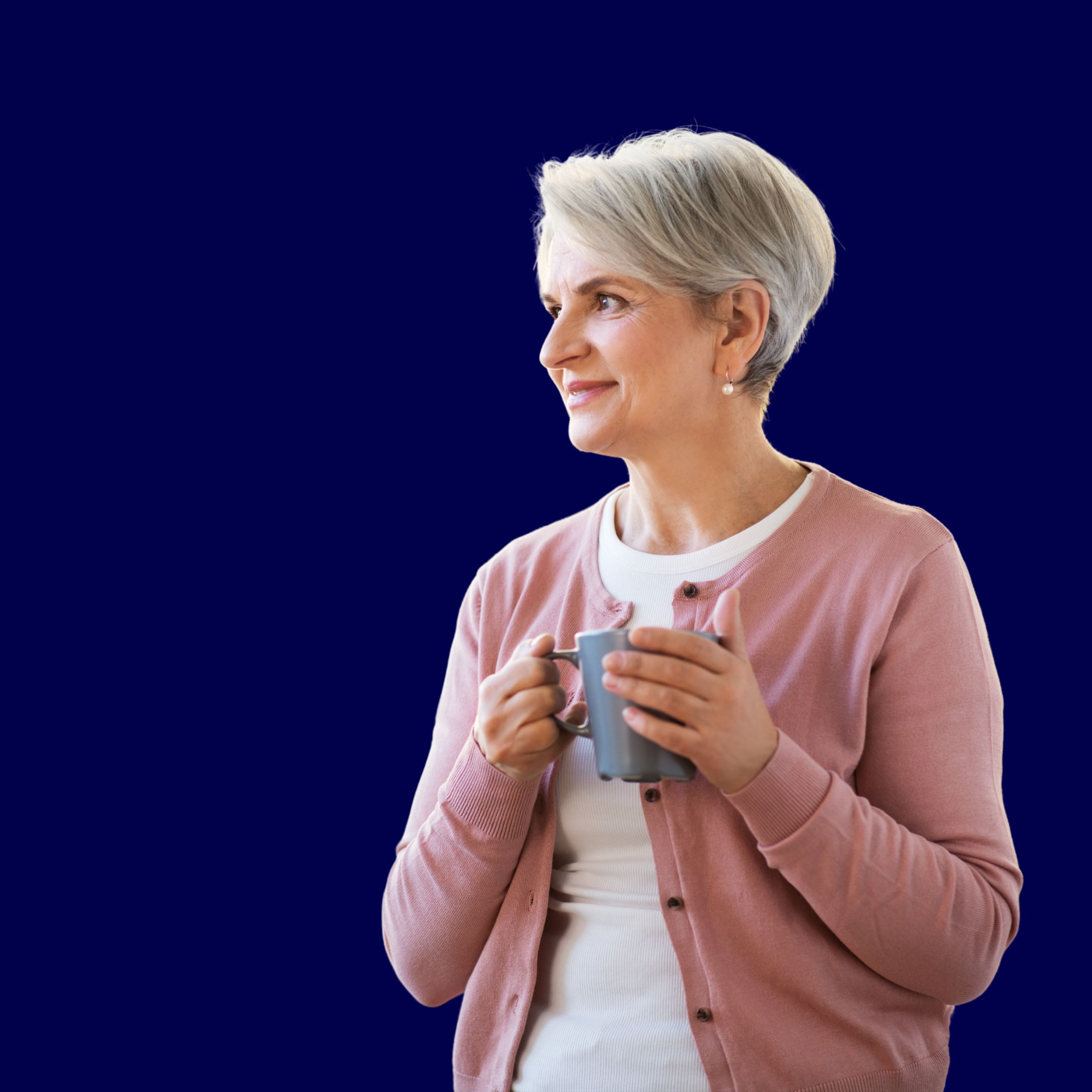 An older woman with short grey hair holding a coffee mug, looking off camera against a deep navy background